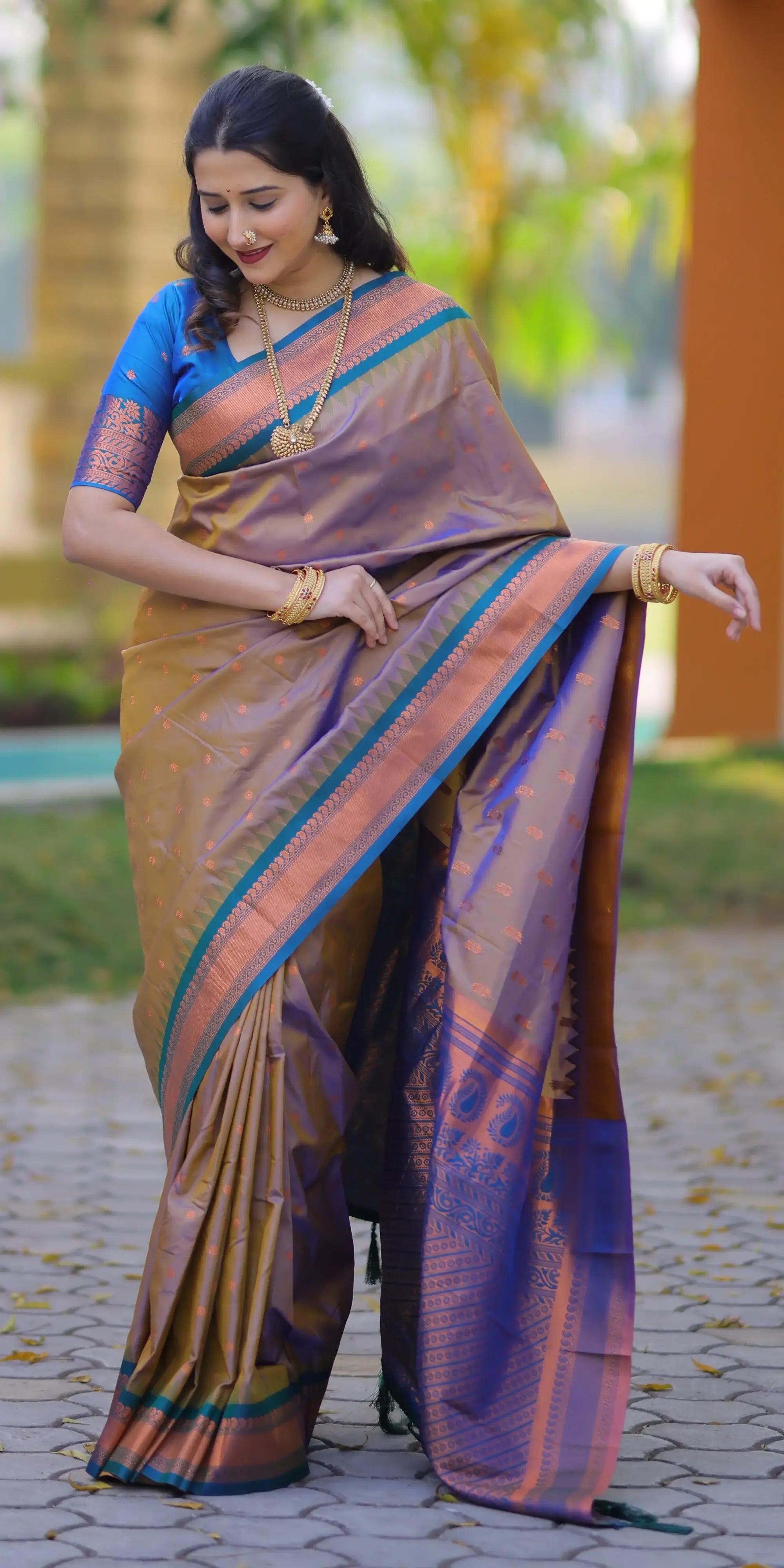 Woman wearing a traditional saree with a blue blouse in an outdoor setting